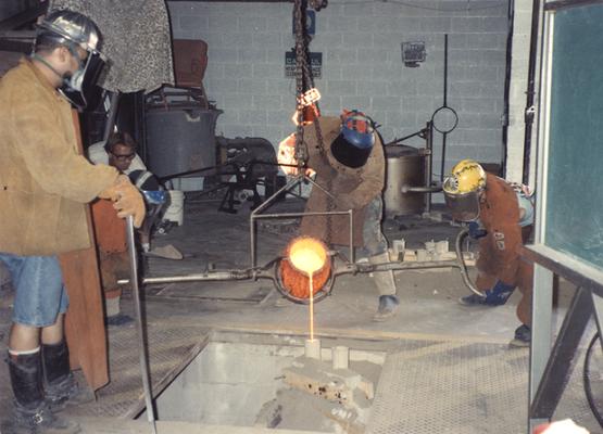 Jack Gron, two unidentified men, Scott Oberlink and Andrew Marsh pouring bronze in the University of Kentucky foundry for the casting of 