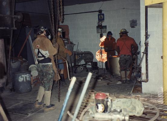 Scott Oberlink, Jack Gron, an unidentified man and Andrew Marsh lifting a crucible out of the furnace at the University of Kentucky foundry for the casting of 