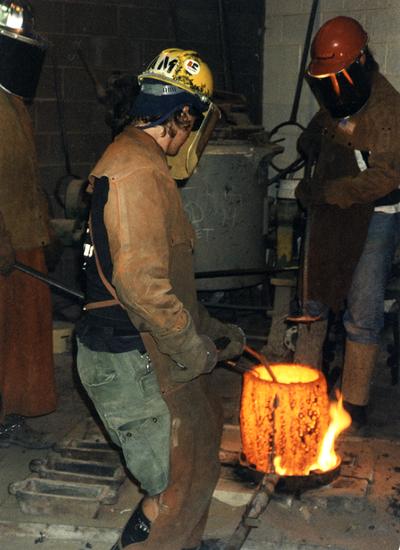 Jack Gron, Andrew Marsh and an unidentified man working with a crucible at the University of Kentucky foundry for the casting of 