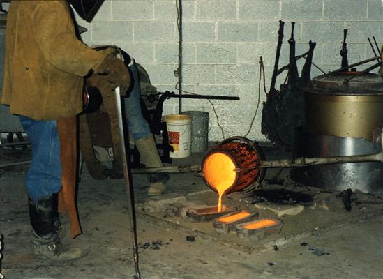 Jack Gron and an unidentified man pouring out left over bronze at the University of Kentucky foundry for the casting of 