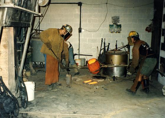 Jack Gron, an unidentified man and Andrew Marsh pouring out left over bronze at the University of Kentucky foundry for the casting of 