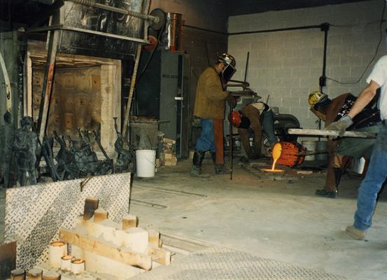 Jack Gron, an unidentified man, Andrew Marsh and another unidentified man pouring out left over bronze at the University of Kentucky foundry for the casting of 