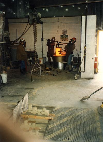 Jack Gron, Andrew Marsh and Scott Oberlink putting the crucible in the furnace at the University of Kentucky foundry for the casting of 