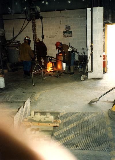 Jack Gron, Andrew Marsh and Scott Oberlink putting the crucible in the furnace at the University of Kentucky foundry for the casting of 