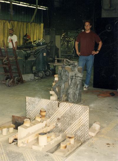 Two unidentified men at the University of Kentucky foundry looking at the cast 