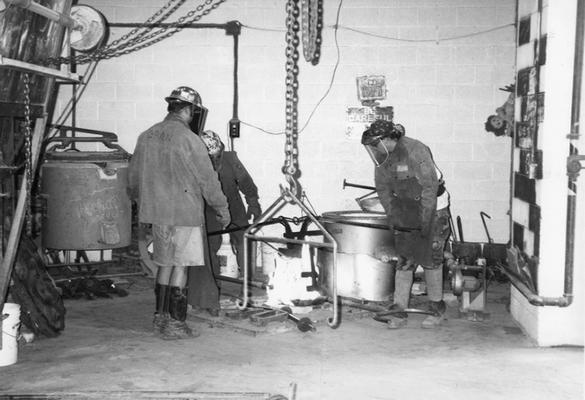 Jack Gron, Andrew Marsh and Scott Oberlink lifting the crucible for the last cast at the University of Kentucky foundry of 