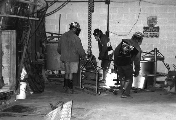 Jack Gron, Scott Oberlink and Andrew Marsh lifting the crucible for the last cast at the University of Kentucky foundry of 