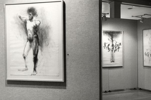 Three charcoal and ink drawings of human figures in an exhibit entitled 