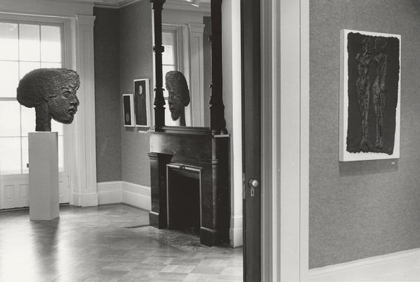 Four cast paper sculptures of human figures, one shaped as a large head, in an exhibit entitled 