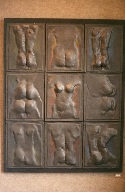 A cast paper sculpture of multiple human figures in an exhibit entitled 