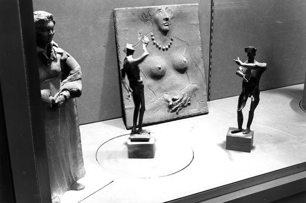 An image of three figure sculptures and a clay relief of a female nude in an exhibit case at the 