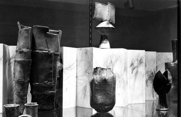An image of multiple ceramic pots and a drawing in an exhibit case at the 