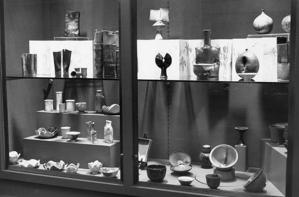 An image of numerous ceramic pots and a drawing in an exhibit case at the 