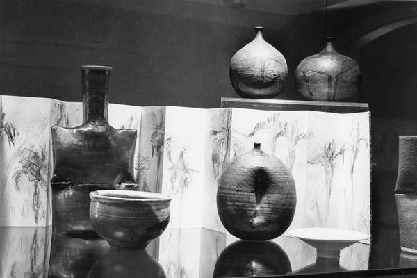 An image of multiple ceramic pots and a drawing in an exhibit case at the 