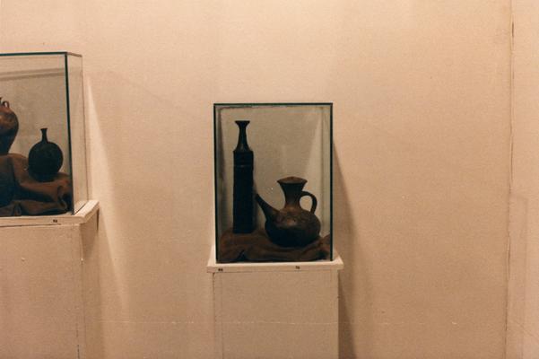 An image of six ceramic vessels in a glass case in the 