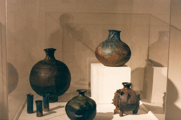 An image of multiple ceramic vessels in a glass case in the 