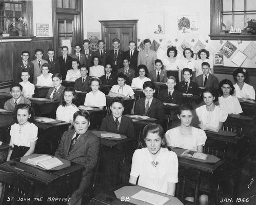 An image of John Tuska and his classmates at the St. John the Baptist School in Brooklyn, New York. Tuska is standing in the back of the classroom. The students have signed their names on the back of this print