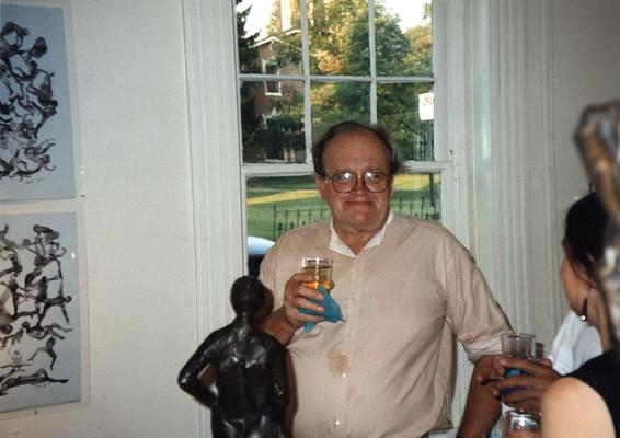 A image of John Tuska with a drink in his hand and unidentified persons viewing artwork at the Heike Pickett Gallery