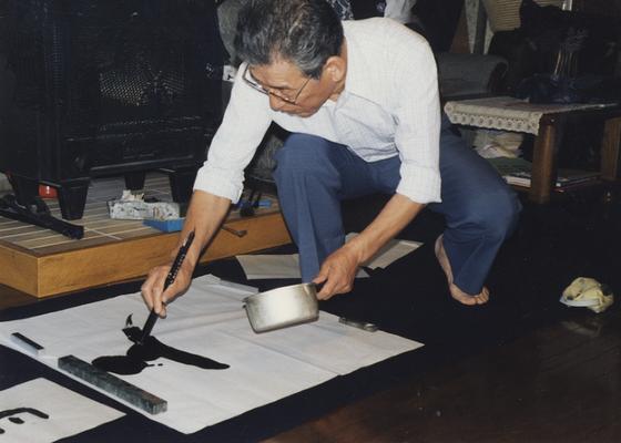 An image a Japanese man named Ishimori-san, painting on a floor. John Tuska visited Japan for the Kentucky Arts Council
