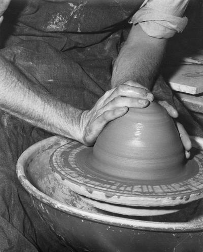An image John Tuska throwing clay on a potter's wheel for a pot