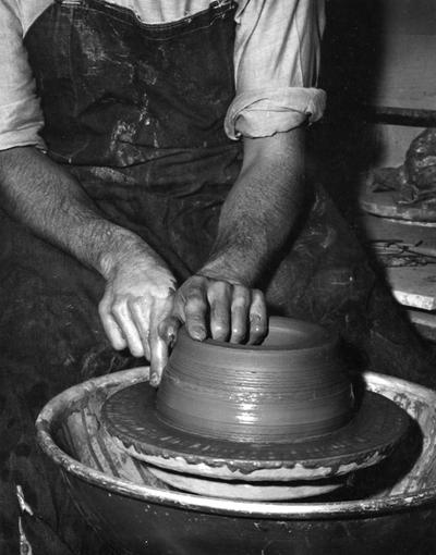 An image John Tuska shaping a clay pot on a potter's wheel