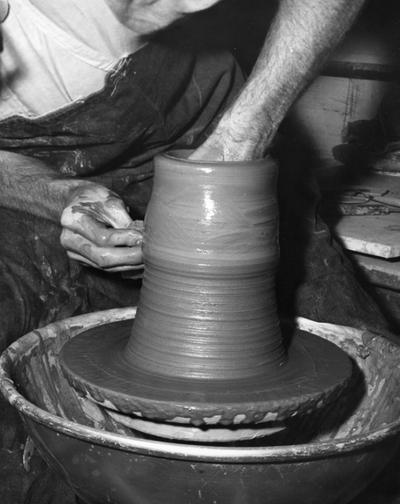 An image John Tuska lifting clay on a potter's wheel