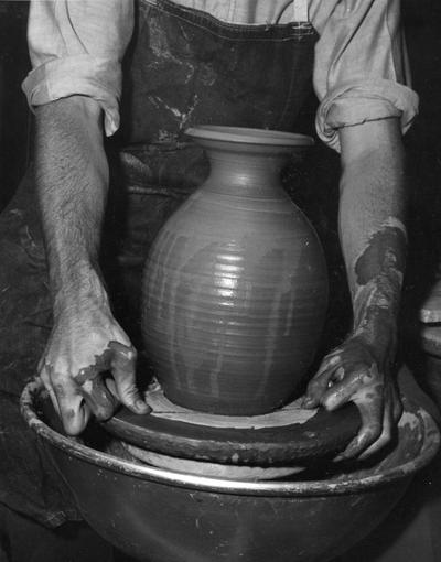 An image John Tuska cutting a clay pot from a potter's wheel