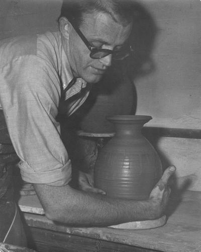 An image John Tuska placing a clay pot to dry before firing