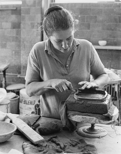An unidentified female student in one of John Tuska's classes, making a base for a pot