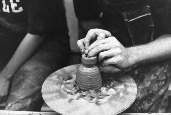 An unidentified student in one of John Tuska's classes, shaping clay on a potter's wheel