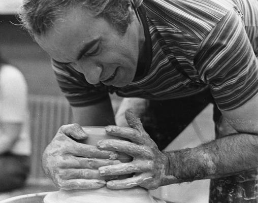Artist Peter Voulkos working with clay on a potter's wheel for a class at the University of Kentucky. John Tuska was in attendance