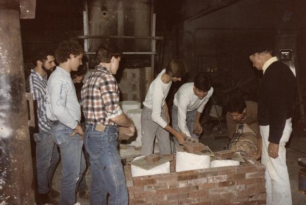 Eight students preparing molds for a pour in the University of Kentucky foundry. The photograph was taken by Zig Gierlach