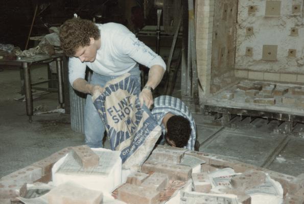 Two students preparing molds for a pour in the University of Kentucky foundry. The photograph was taken by Zig Gierlach