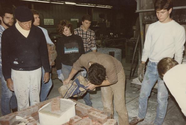 Eight students preparing molds for a pour in the University of Kentucky foundry. The photograph was taken by Zig Gierlach