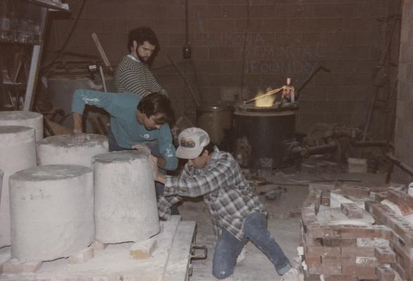 Three students moving molds in the University of Kentucky foundry. The photograph was taken by Zig Gierlach