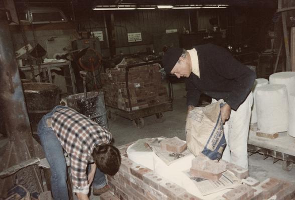 Two students preparing molds for a pouring in the University of Kentucky foundry. The photograph was taken by Zig Gierlach
