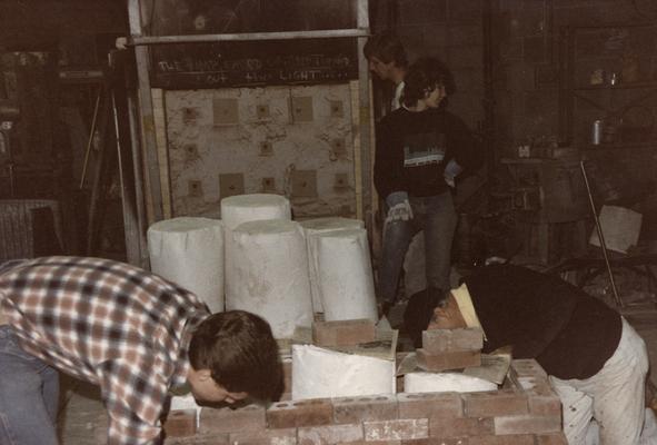 Four students preparing molds for a pouring in the University of Kentucky foundry. The photograph was taken by Zig Gierlach