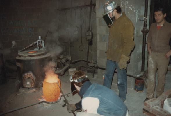 Jack Gron and two students working with a crucible in the University of Kentucky foundry. The photograph was taken by Zig Gierlach