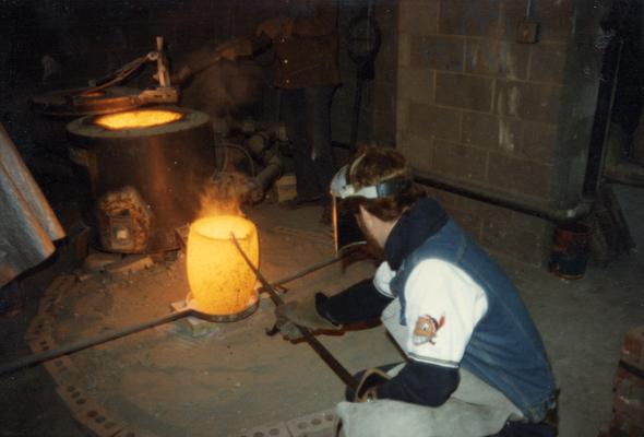 Jack Gron and a student working with a crucible in the University of Kentucky foundry. The photograph was taken by Zig Gierlach