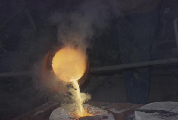 Pouring molten metal from a crucible in the University of Kentucky foundry. The photograph was taken by Zig Gierlach