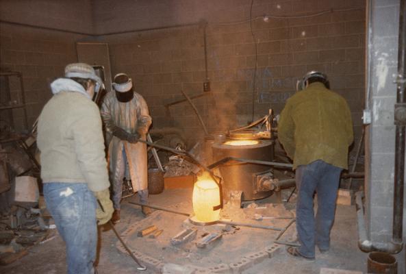 John Tuska, an unidentified student and Jack Gron preparing to pour molten metal into a mold in the University of Kentucky foundry. The photograph was taken by Zig Gierlach
