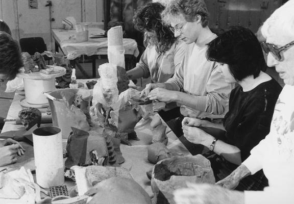 A group of several students working on clay around a table in John Tuska's ceramics class at the University of Kentucky