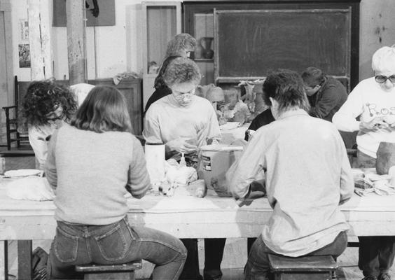A group of several students working on clay around tables in John Tuska's ceramics class at the University of Kentucky