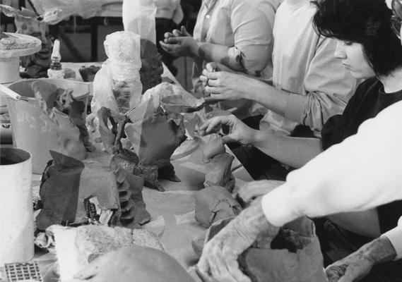 A group of several students working on clay around a table in John Tuska's ceramics class at the University of Kentucky