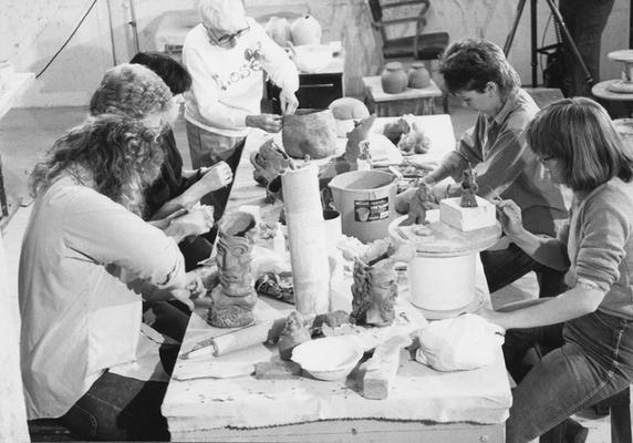 A group of several students working on clay around a table in John Tuska's ceramics class at the University of Kentucky