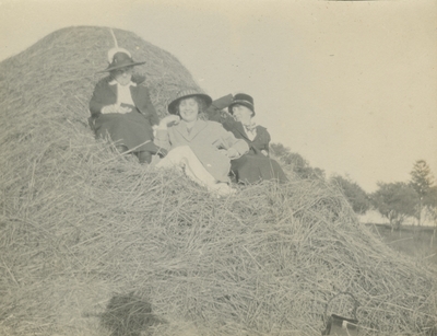 3 women sitting in a hay stack