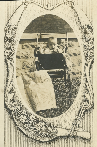 postcard with a decorative border, a baby sitting in a baby carriage