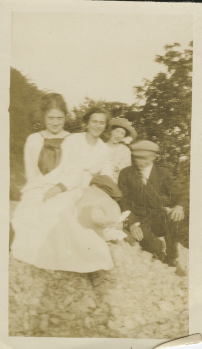 3 women and 1 man sitting down outside together