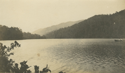 a nature scene with 2 people in a boat off in the distance