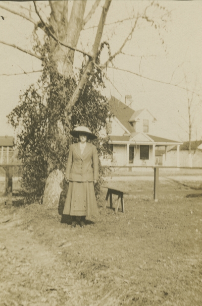 a woman standing outside next to a tree